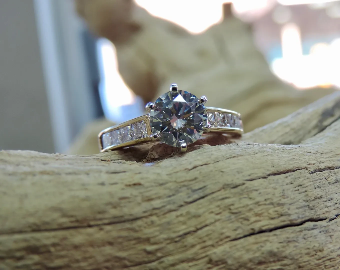 Round diamond engagement ring on driftwood
