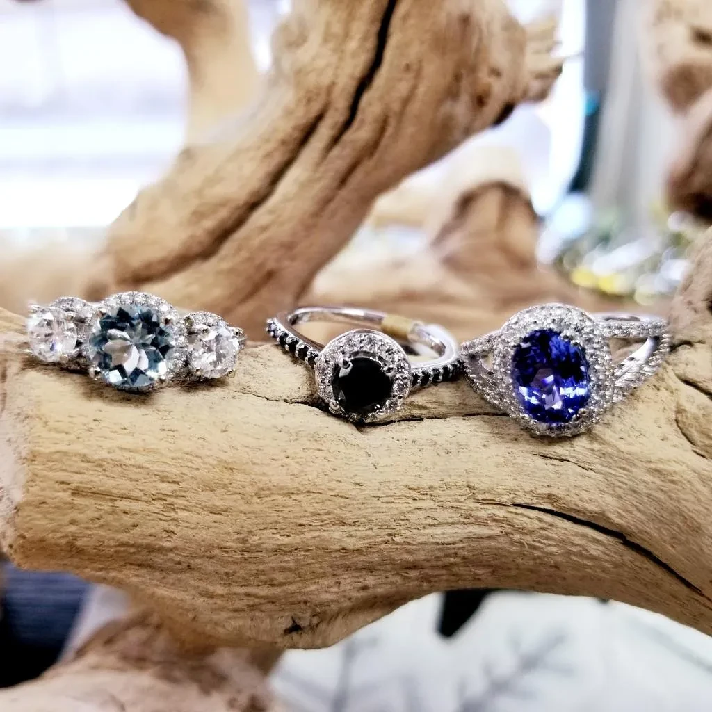 Several gemstone rings displayed on driftwood branch