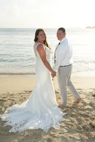 Newlyweds holding hands on the beach